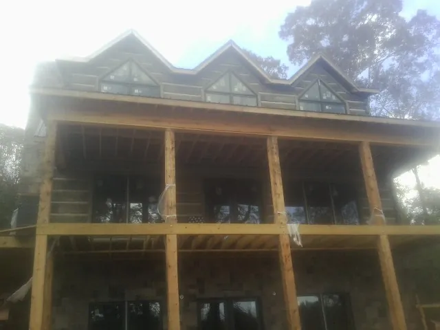 Dormers and porch framing on a large log home under construction — Roof Coating work by our crew in Eastview