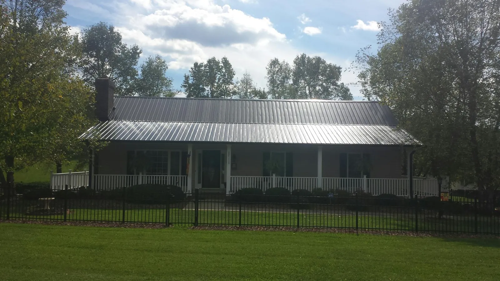 Gray metal roof on a brick ranch with a full width front porch — Gutter Guard Installation work by our crew in Eastview