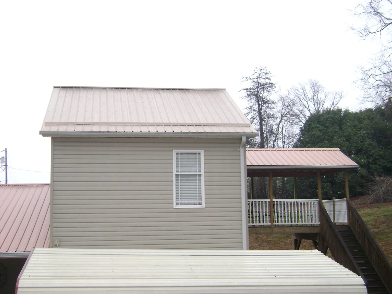 Tan metal roofs on a two story addition and attached porch, from a Roof Replacement job in Eastview