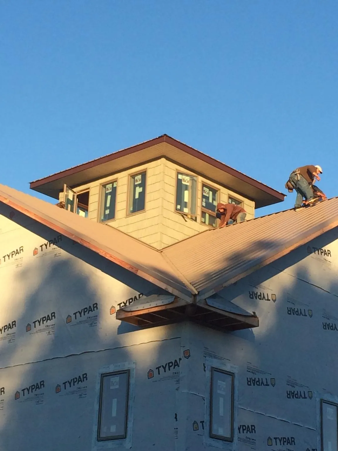 Roofers working around a rooftop cupola on a new metal roof at sunset — Roof Waterproofing in Eastview by Roofing Brothers